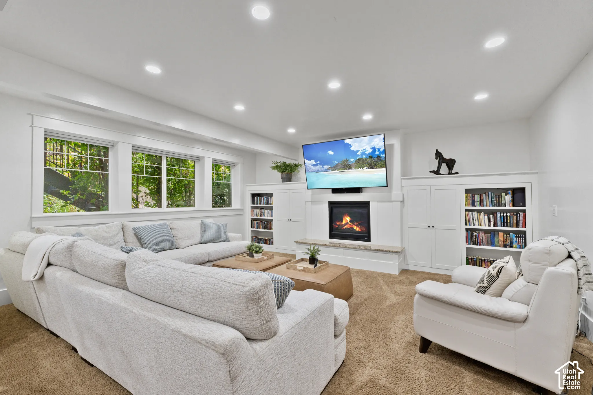 Living area featuring a built-in fireplace, custom cabinetry with integrated shelving, recessed lighting, and large windows with grid detailing