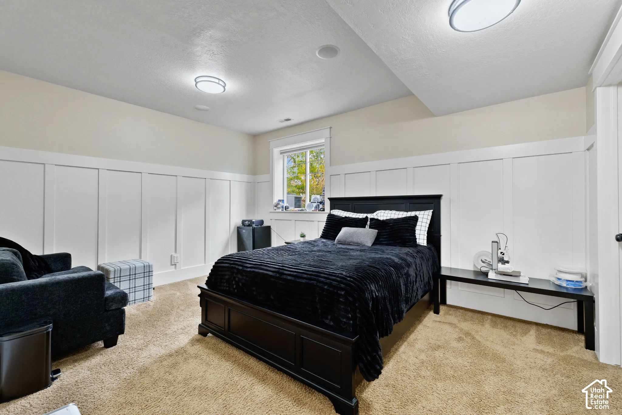 Interior space featuring white board-and-batten wainscoting, neutral carpeting, and dual flush-mount ceiling light fixtures