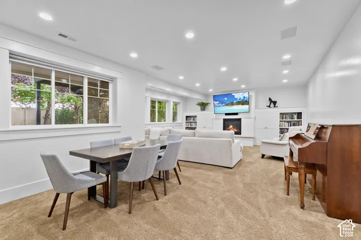 Open-concept area featuring recessed lighting, a built-in fireplace, custom white cabinetry, and large windows