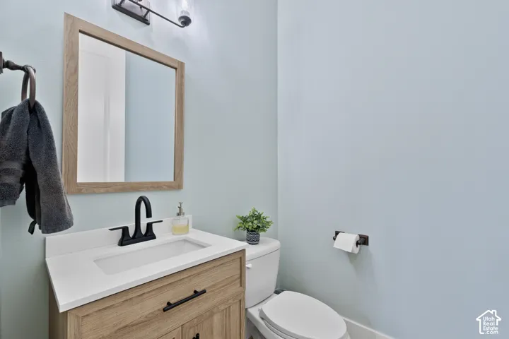 Wood-finish vanity with a rectangular sink, quartz countertop, matching wood-framed mirror, and matte black hardware