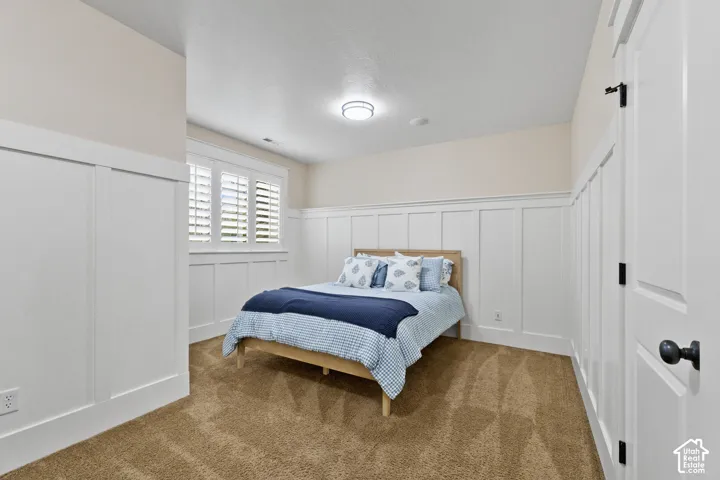 Interior space featuring floor-to-ceiling white board-and-batten wainscoting, wall-mounted shutter treatments, neutral carpeting, and a flush-mount ceiling light fixture