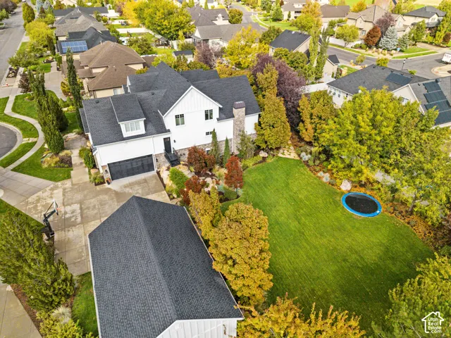 Two-story residence featuring a white vertical-siding exterior, stone masonry accents, an attached three-car garage, and a manicured lawn