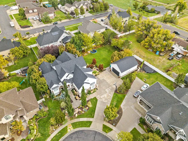 Aerial perspective of a detached multi-car garage, expansive manicured lawn, concrete driveway, and mature landscaping