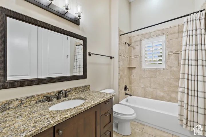Bathroom featuring a stone-surface vanity with an integrated basin, wood-finish cabinetry, framed wall mirror, three-light fixture, and a tile-surround tub with an inset window