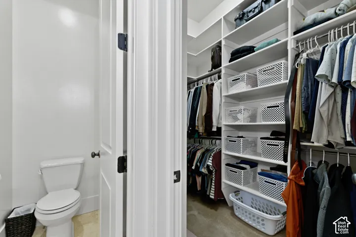 Walk-in closet featuring white floor-to-ceiling custom shelving, multiple hanging rods, and integrated cabinetry