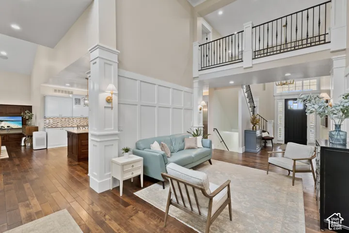 Two-story foyer featuring a staircase with wrought iron railings, extensive wall wainscoting, recessed lighting, and wood-finish flooring