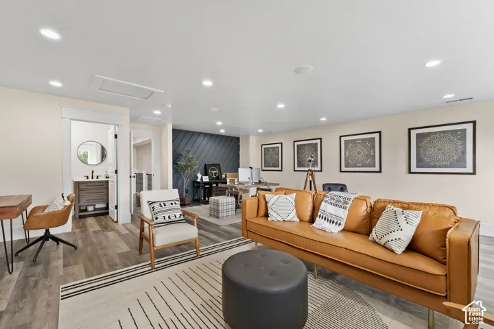 Spacious living area featuring wood-finish flooring, recessed lighting, and an accent wall with diagonal paneled detailing