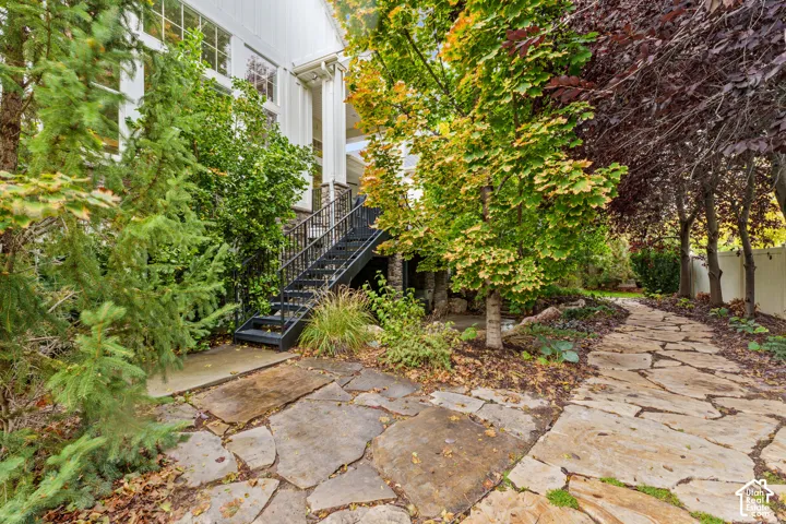 Flagstone patio and pathway, metal exterior staircase, vertical board-and-batten siding, and stone foundation detailing