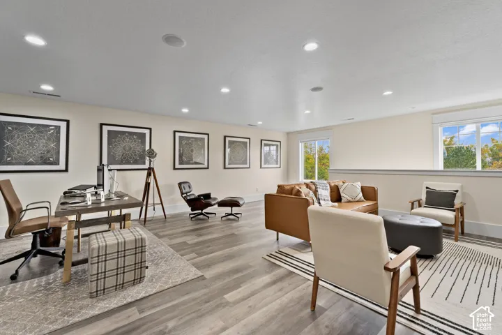 Spacious living area featuring wood-finish flooring, recessed lighting, and multiple windows