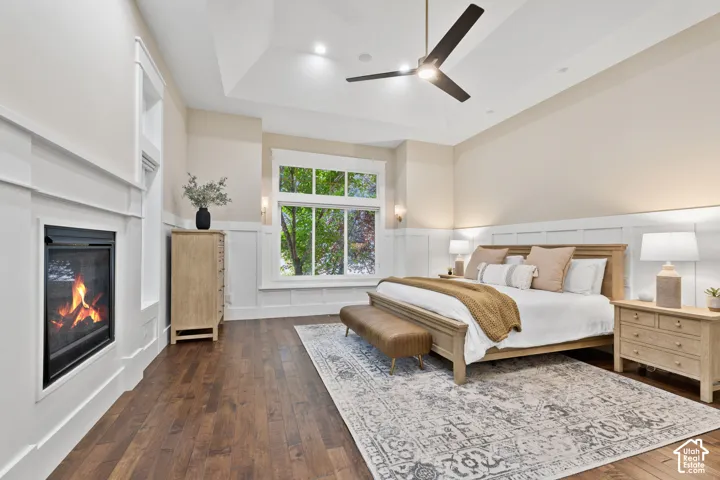 Tray ceiling with recessed lighting, wood-finish flooring, white wainscoting, and a built-in fireplace