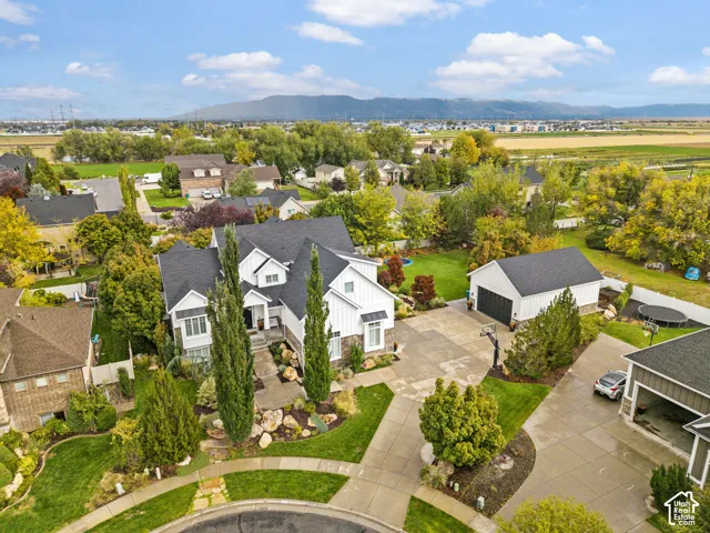 Multi-level residential property featuring board-and-batten siding, stone masonry accents, an attached multi-car garage, expansive manicured grounds, and a paved stone driveway