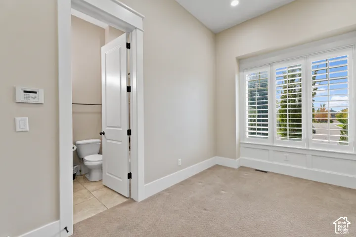 Triple-pane bay window featuring white plantation shutters and wainscoting detail, complemented by interior door with architectural casing and neutral carpeting