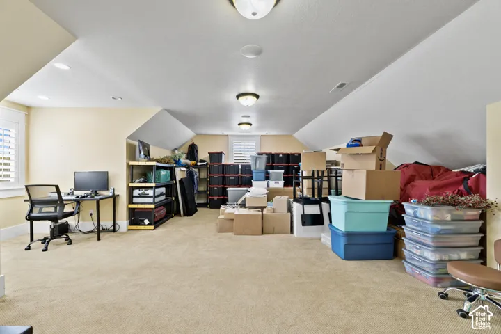 Expansive room featuring vaulted ceilings, neutral wall-to-wall carpeting, recessed lighting, and interior shutters