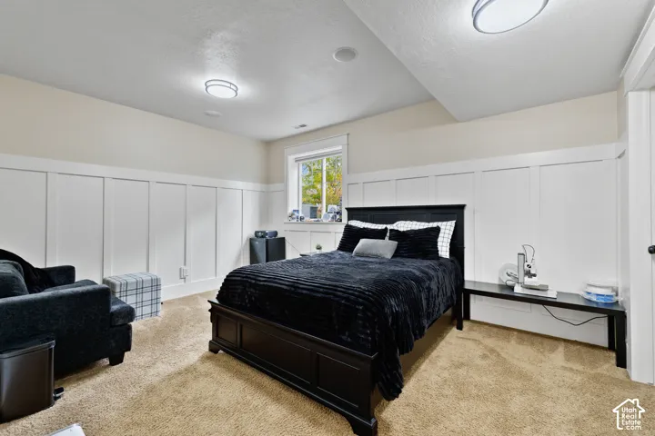Interior space featuring white board-and-batten wainscoting, neutral carpeting, and dual flush-mount ceiling light fixtures