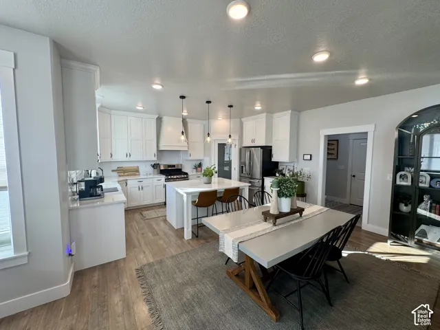 Kitchen featuring white shaker cabinetry, quartz countertops, a central island, recessed ceiling lighting, and wood-finish flooring