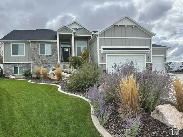 Exterior facade featuring horizontal siding and vertical board-and-batten accents, stacked stone veneer, a multi-gabled roofline, and landscaped grounds with stone edging