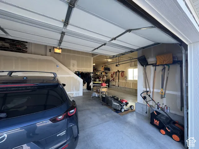 Spacious multi-car garage featuring a concrete floor, high ceilings, natural light from a window, and overhead door mechanism
