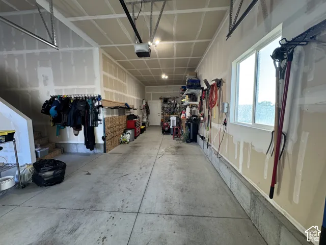 Attached garage featuring a concrete floor, high-clearance ceiling with an automatic opener, and a side window