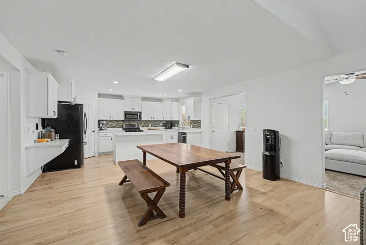 Open concept kitchen with light wood-finish flooring, white cabinetry, and a tile backsplash