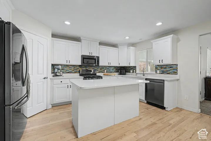 Kitchen featuring white cabinetry, a center island, wood-finish flooring, recessed lighting, and a mosaic tile backsplash
