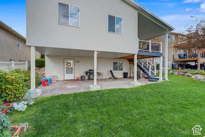 Lower level patio with a paver surface, covered overhead area, and access to the upper deck via exterior stairs