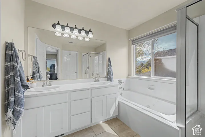 Dual vanity with white cabinetry, large mirror, and tiled flooring
