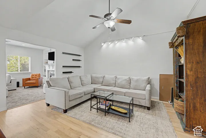 Vaulted ceiling with a ceiling fan, recessed track lighting, wood-finish flooring, and an expansive doorway