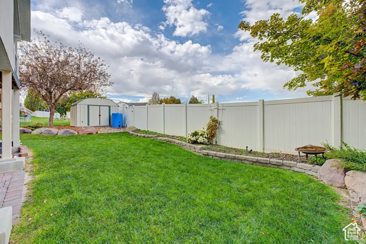 Expansive backyard featuring a manicured lawn, a white privacy fence, and a storage shed