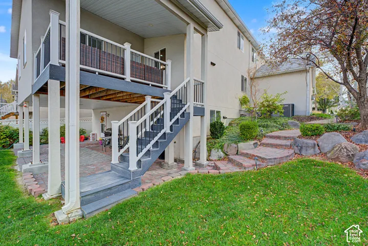 Multi-level exterior with an elevated deck, a lower-level patio, and a retaining wall with stone steps