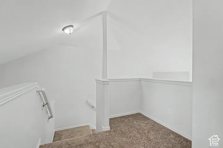 Carpeted staircase with white handrail and white wall paneling