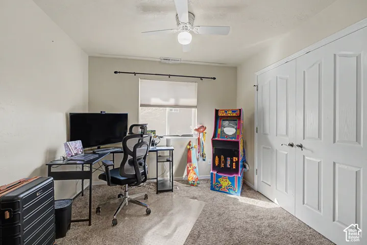 Neutral wall paint, ceiling fan, window with blinds, dual closet doors, and carpeted flooring