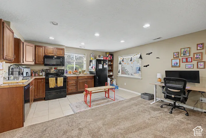 Kitchen with wood-finish cabinetry, black appliances, and tile flooring