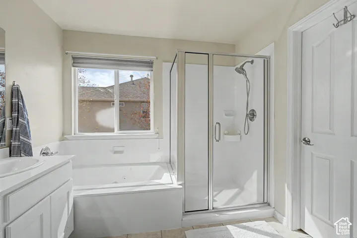 Built-in soaking tub, separate shower enclosure with glass door, vanity with integrated sink, and white paneled door