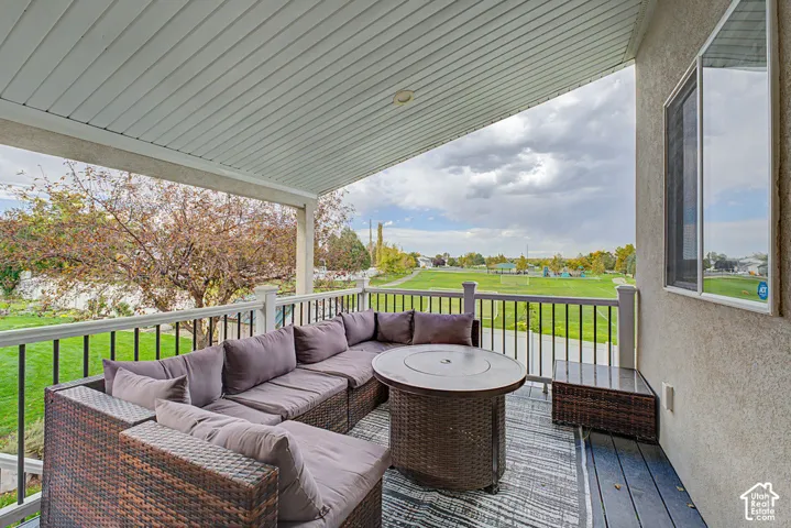 Covered outdoor deck with white railing and black spindles, featuring a textured exterior wall and a window