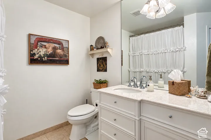 Bathroom featuring a vanity with a light-toned stone countertop, integrated undermount sink, chrome faucet, white cabinetry, and a full-height wall mirror
