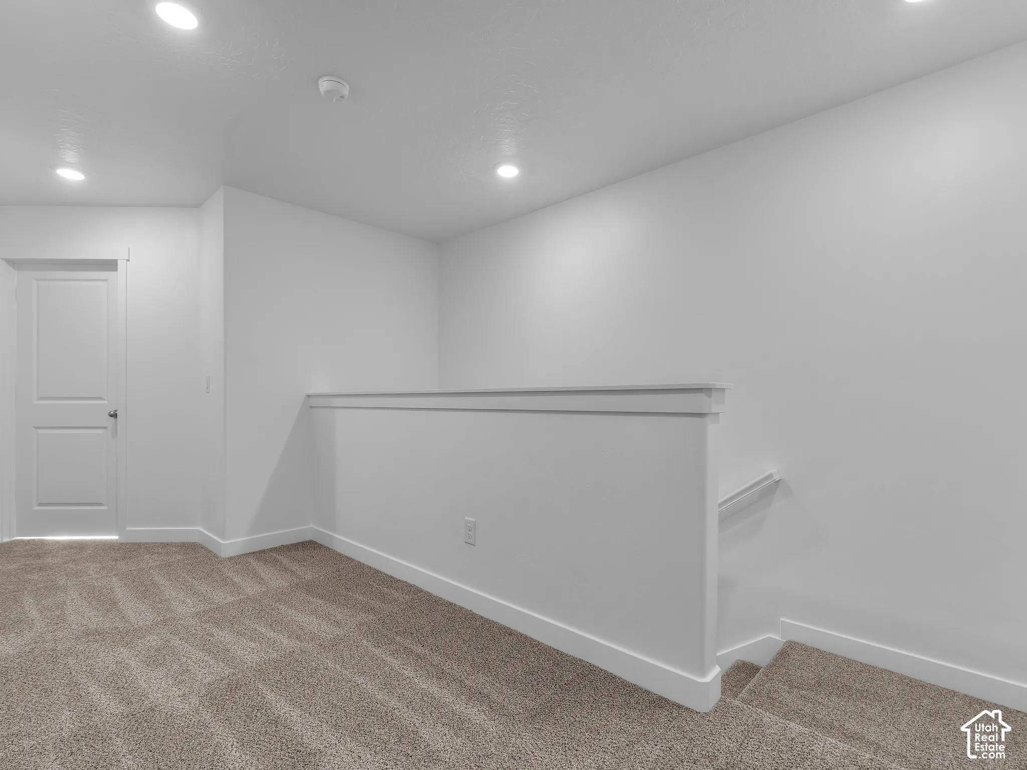 Neutral-toned carpeting, recessed ceiling lighting, and a solid-core interior door with a white finish