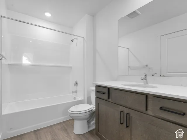Bathroom featuring a dark wood-finish vanity with a light-toned countertop, integrated oval sink, matte black hardware, and a tub-shower combination with a full-width mirror