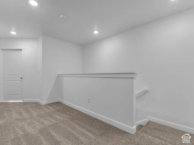 Neutral-toned carpeting, recessed ceiling lighting, and a solid-core interior door with a white finish