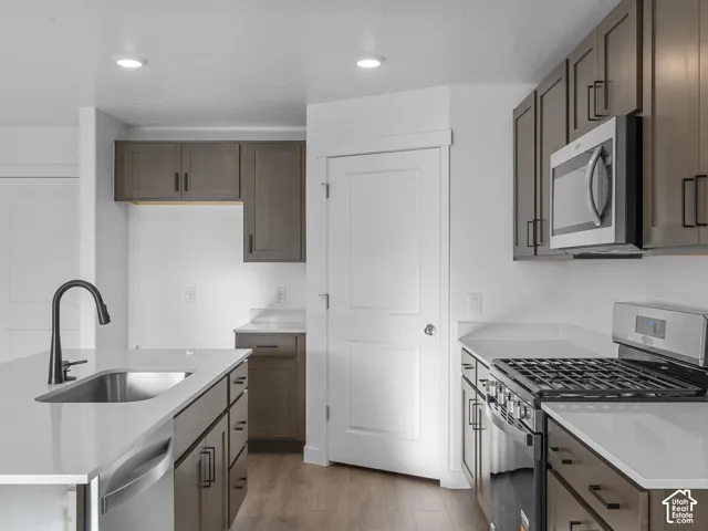 Kitchen featuring shaker-style cabinetry, quartz countertops, a stainless steel gas range, recessed lighting, and a kitchen island with a single-basin sink and matte black faucet