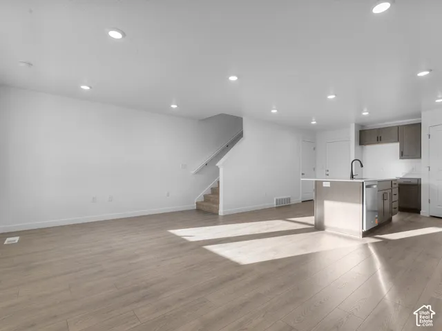 Open-concept interior featuring wood-finish flooring, recessed lighting, and a central kitchen island with a matte black faucet
