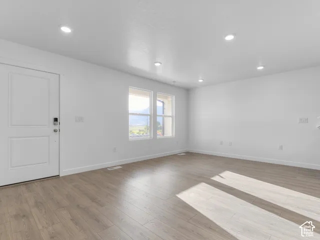 Interior space featuring wood-finish flooring, recessed lighting, dual windows, and a paneled entry door