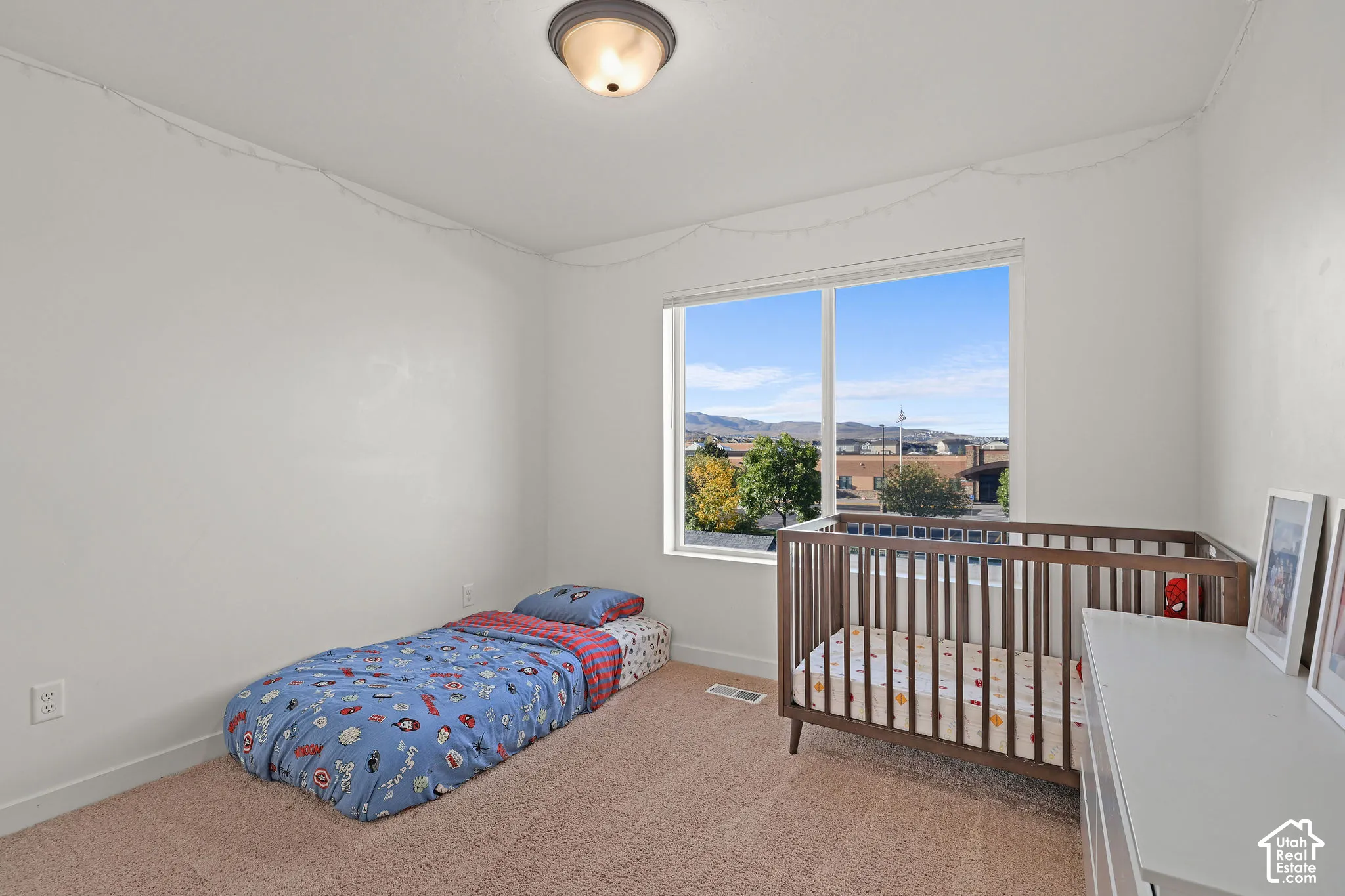 Room featuring neutral wall tones, wall-to-wall carpeting, a large picture window, and a flush-mount ceiling light fixture, accented by distant mountain scenery