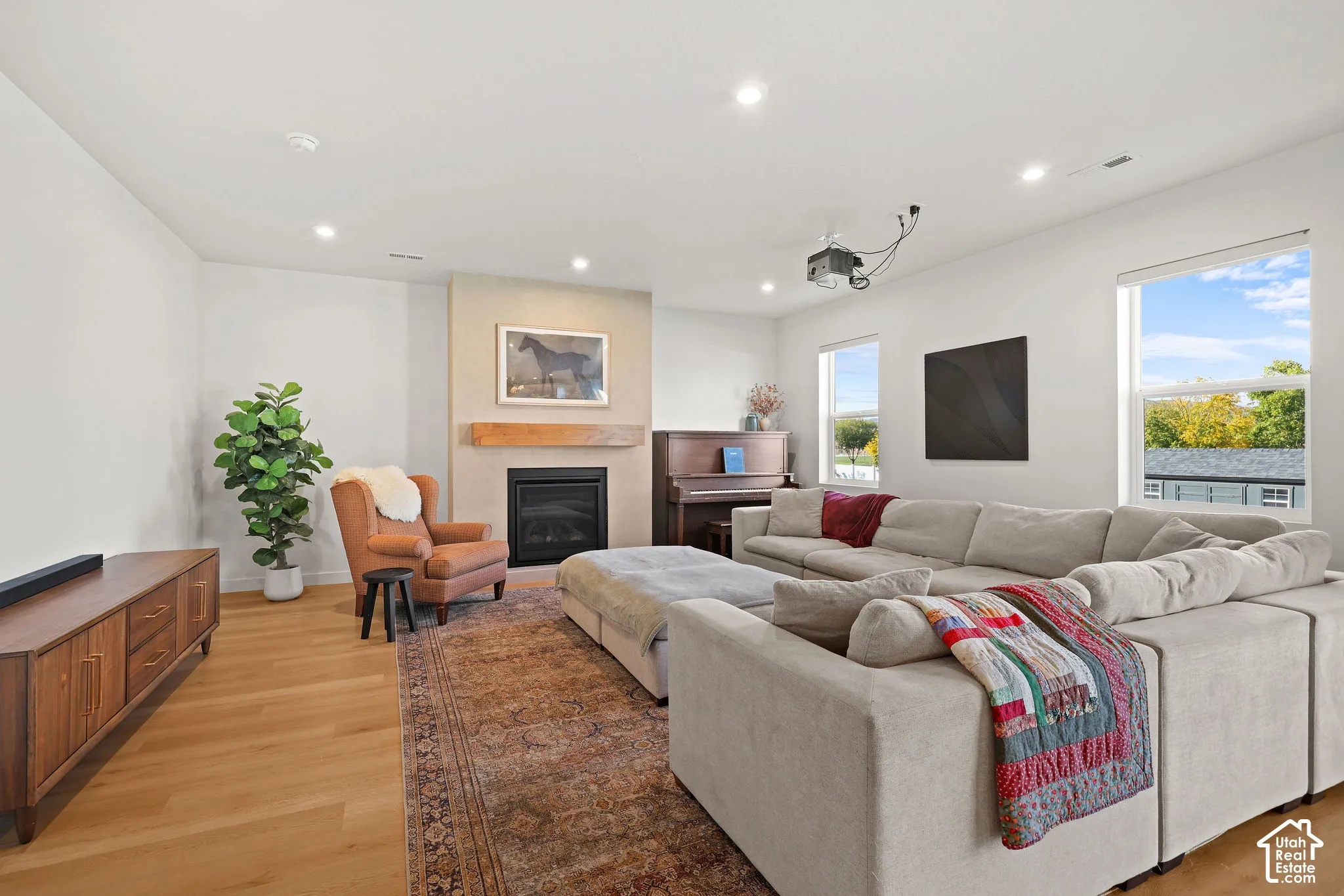 Living area featuring wood-finish flooring, recessed lighting, and a fireplace with a masonry surround and wood mantel