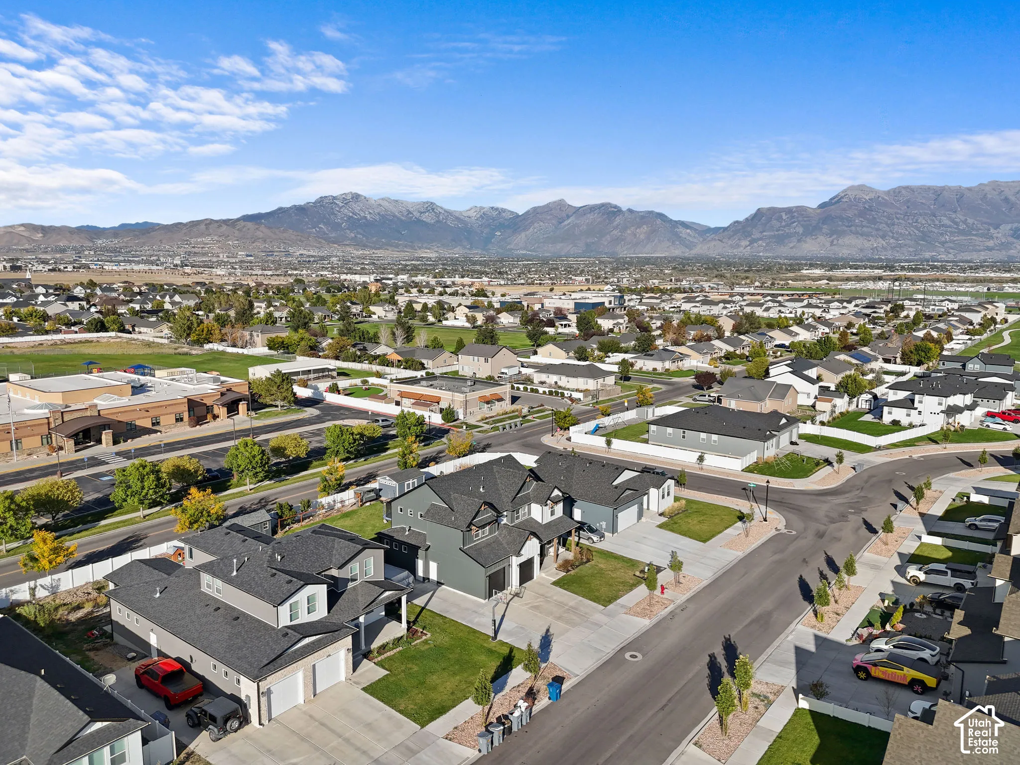 Aerial perspective of a multi-level residence featuring dark-toned siding, asphalt shingle roofing, attached two-car garages, concrete driveways, and mountain scenery