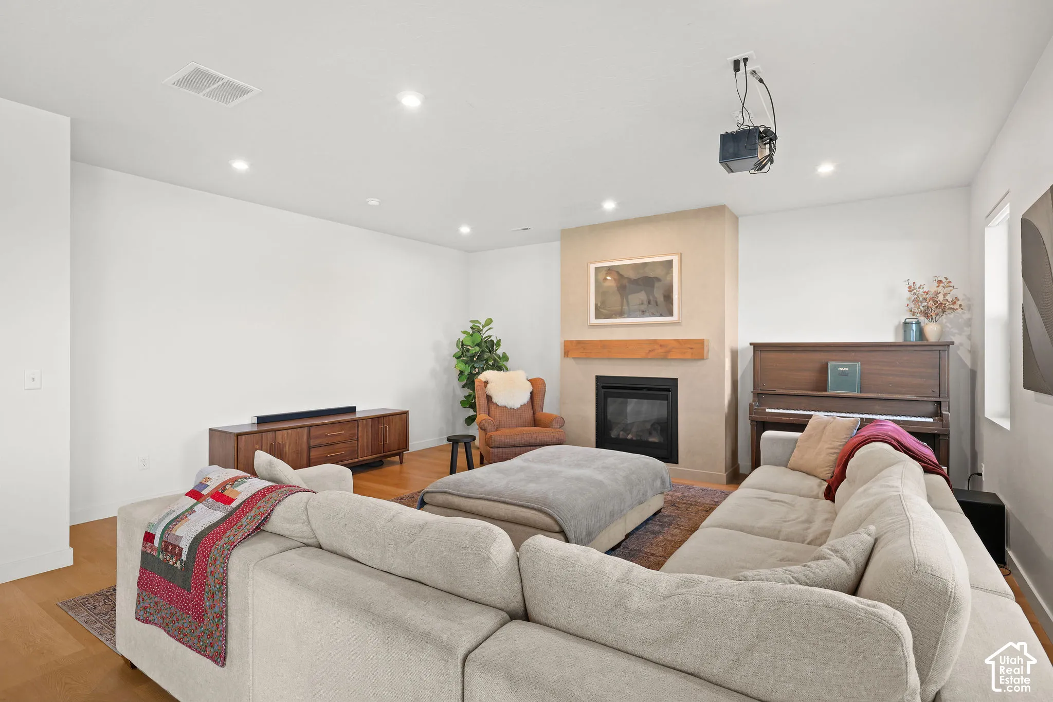 Living area featuring wood-finish flooring, recessed lighting, and a fireplace with a textured surround and natural wood mantel