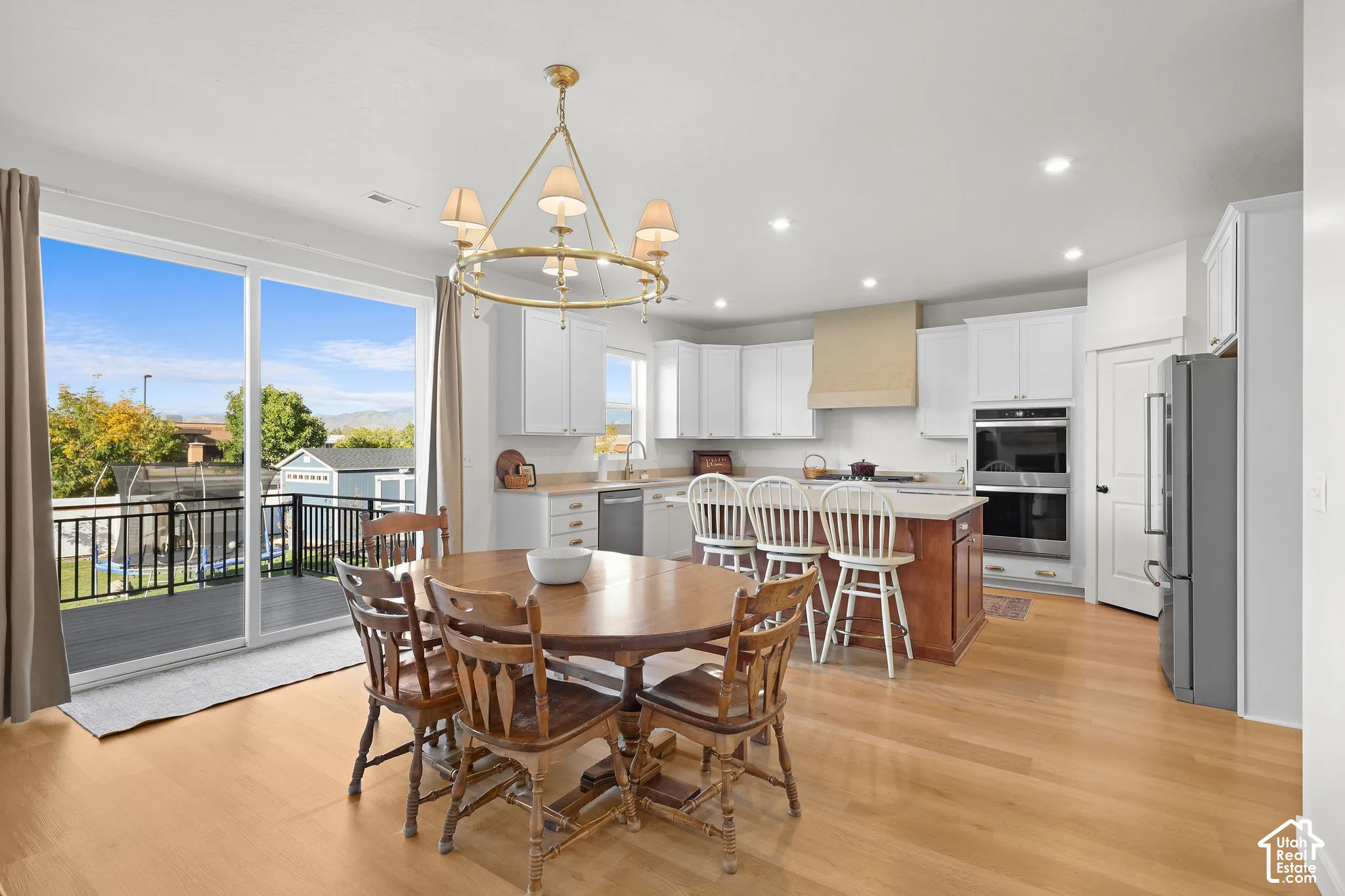 Kitchen featuring a center island, wood-finish flooring, custom range hood, recessed lighting, and stainless steel double wall ovens