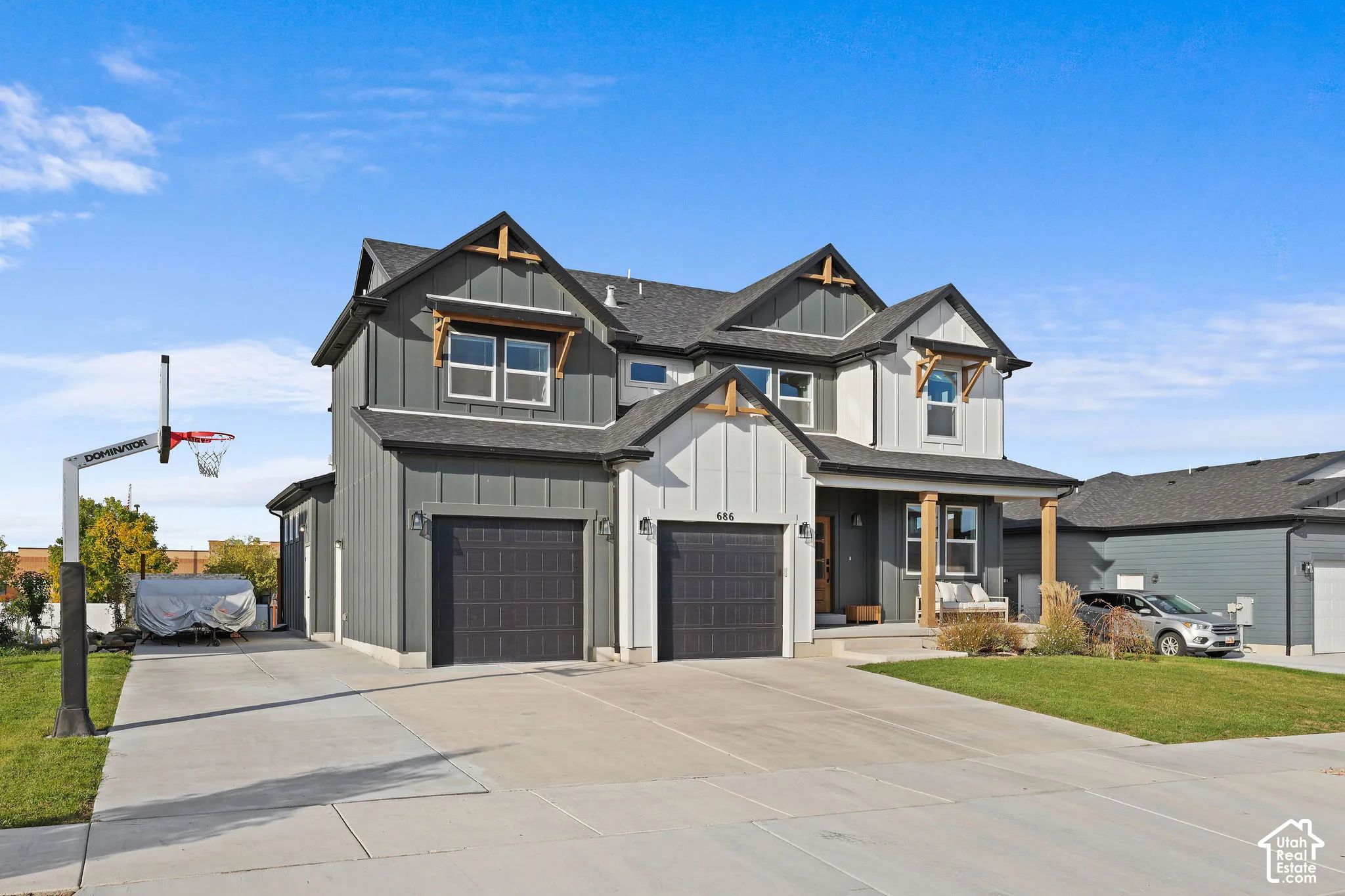 Multi-level residence featuring board-and-batten siding, decorative wood gable brackets, a covered front porch, and a two-car garage