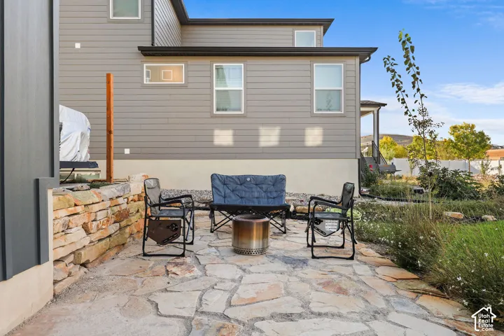 Flagstone patio featuring a natural stone retaining wall and horizontal lap siding exterior
