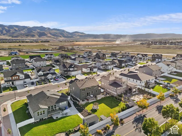 Aerial view of residential lots featuring manicured lawns, fenced backyards, paved driveways, and mountain scenery