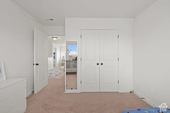 Room featuring neutral-toned carpeting, dual-panel interior doors, and white-painted millwork